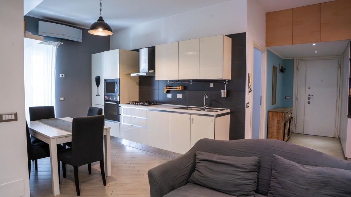 La cucina con il tavolo e le sedie, i mobili bianchi e il piano scuro