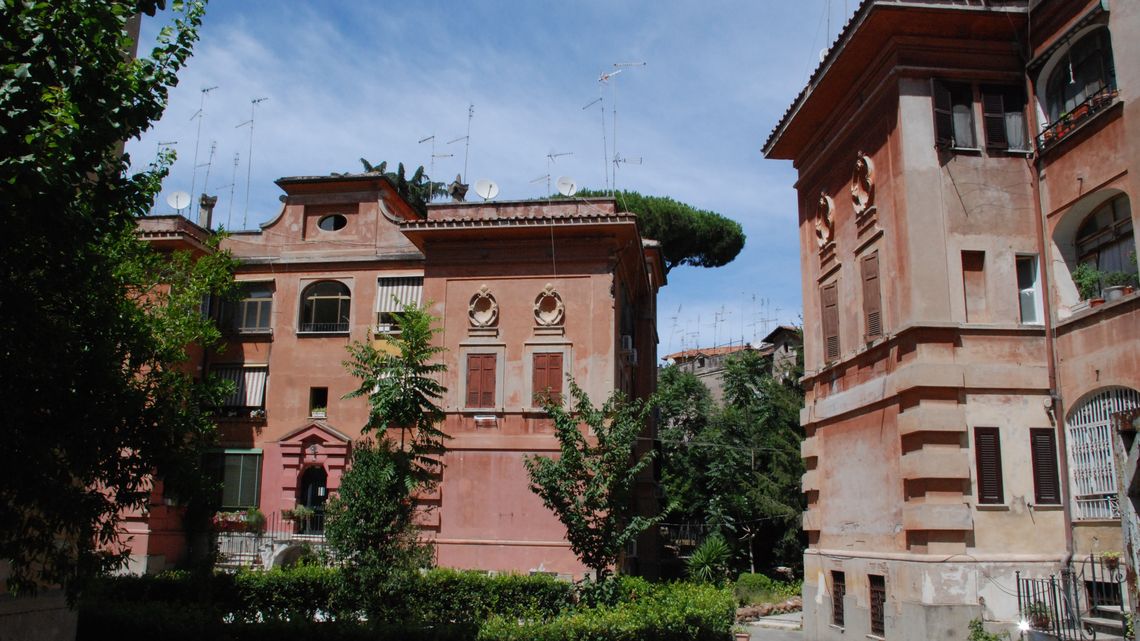 Il cortile di un lotto della Garbatella, con le palazzine rosa e un pino